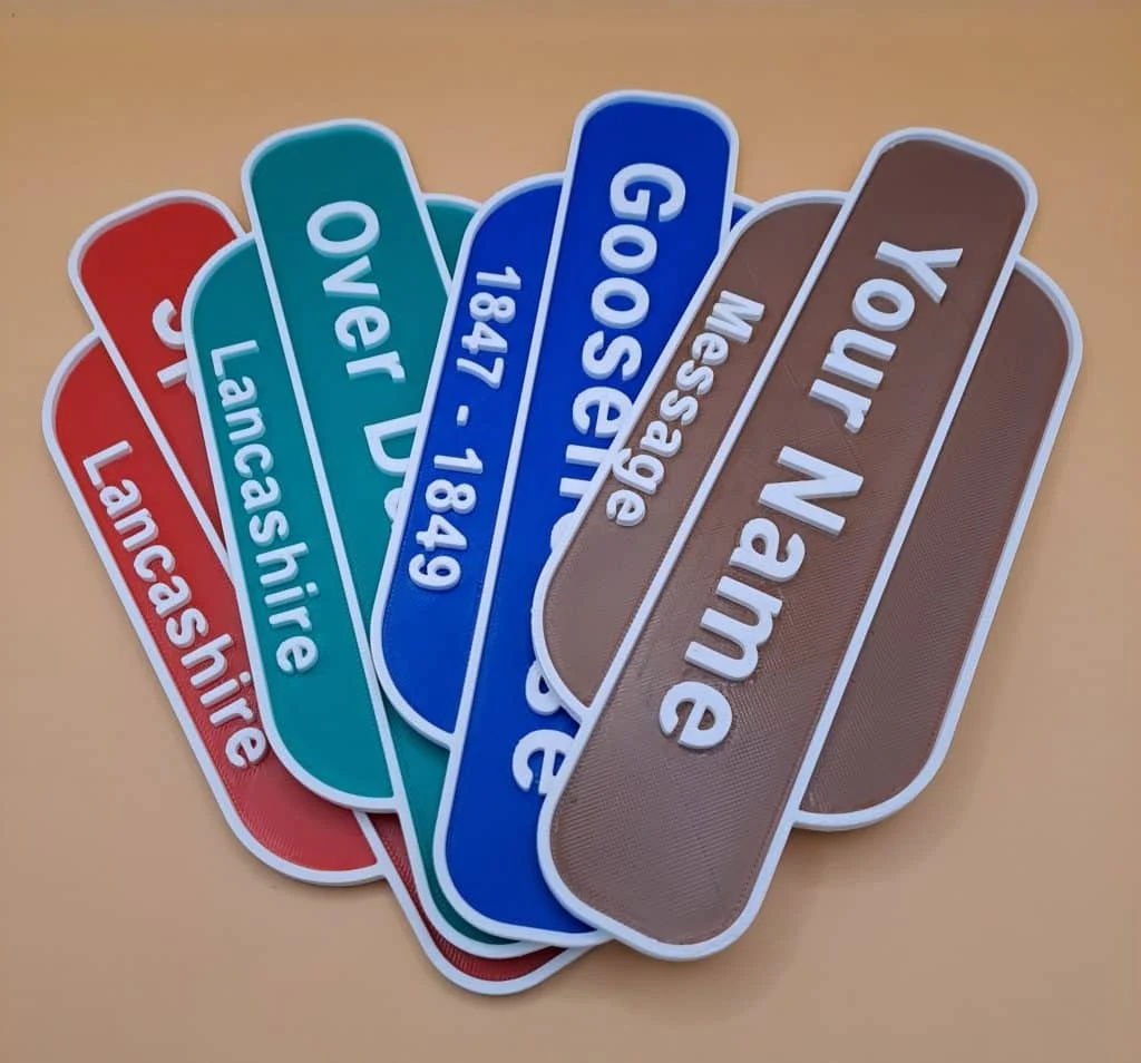 Colourful personalised railway signs made by Harle.Tech, with raised lettering and white borders.