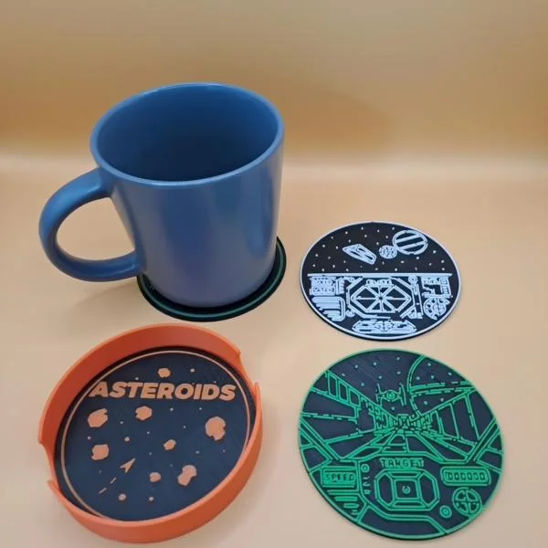 Retro gaming coasters in different colours beside a blue mug.
