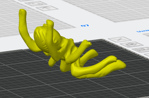 Yellow 3D spider model positioned upside down at an angle on a virtual print bed inside slicer software.